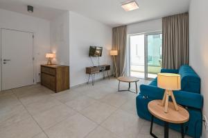 a living room with a blue couch and a tv at VILLA CALA, Hotel Rooms&Apartments in Novalja