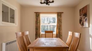a dining room table with two chairs and a window at Jubilee Cottage in Rusland
