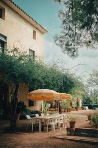 une table et des chaises avec des parasols en face d'un bâtiment dans l'établissement Casa Rural Cal Gotlla, à Vilobi Del Penedes