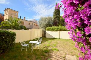 podwórze z dwoma krzesłami i stołem oraz fioletowymi kwiatami w obiekcie Villa Palma 2 w Palma de Mallorca