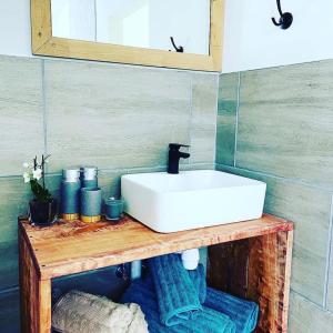 umywalkę w łazience na drewnianym blacie z lustrem w obiekcie Kingsbrook Pods w mieście Clarens