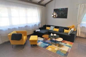 ein Wohnzimmer mit einem schwarzen Sofa und gelben Stühlen in der Unterkunft Mill Valley Villa in Koblenz