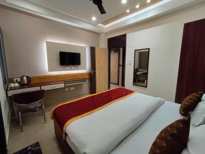 ein Schlafzimmer mit einem großen Bett und einem TV an der Wand in der Unterkunft Royal Rooms and Banquet in Lucknow