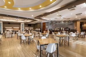 une salle à manger avec des tables et des chaises blanches dans l'établissement Hotel j-Metropolis, à Hsinchu