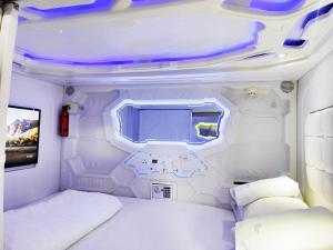 Dieses weiße Zimmer verfügt über ein Bett und einen TV. in der Unterkunft Met A Space Pod @Phrom Phong in Bangkok