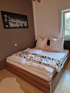 a bedroom with a large bed with white sheets and a window at Ferienwohnung Bayernbrise in Rohrdorf