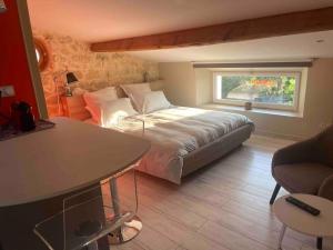 Schlafzimmer mit einem Bett, einem Fenster und einem Tisch in der Unterkunft Studio with AC, pool & garden, 2km St Emilion in Saint-Christophe-des-Bardes