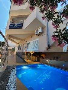 a villa with a swimming pool in front of a house at Apartments Proxima in Trogir