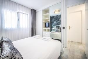 a white bedroom with a large bed and a television at Apartamento Alma in Puerto del Carmen
