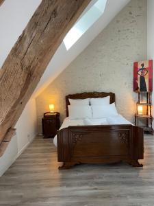 a bedroom with a wooden bed in a attic at La Maison des anges avec jardin : proche beauval in Billy