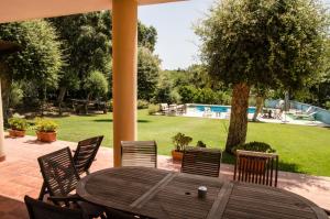 a wooden table and chairs on a patio with a pool at Estancia en plena naturaleza-Andrea in Sotogrande