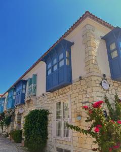 un edificio con ventanas azules y flores. en F&G BUTİK HOTEL, en Alacati
