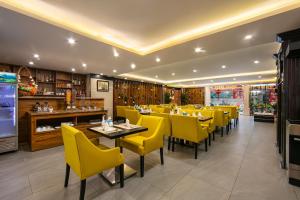 ein Restaurant mit gelben Stühlen und Tischen in einem Zimmer in der Unterkunft San Hanoi Hotel in Hanoi
