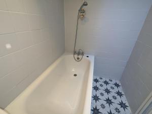 a white bath tub with a shower in a bathroom at Hoxton/Shoreditch Rooms in London