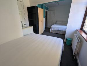 a bedroom with a white bed and a bathroom at Hoxton/Shoreditch Rooms in London