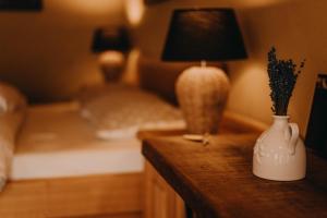 Polzela的住宿－Lavender Hill, Eko Resort & Wellness，一间卧室配有一张床和一张桌子,配有一盏灯和花瓶