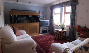 Home Farm Bed and Breakfast في موير أوف أورد: غرفة معيشة بها كنبتين بيضاء وتلفزيون