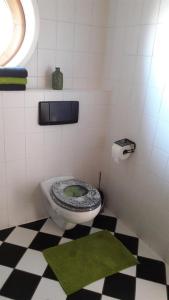 a bathroom with a toilet with a black and white checkered floor at Ferienwohnung Am Gässchen in Scheiden