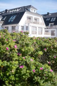 Uma casa branca com flores cor-de-rosa à frente. em DAS LORNSEN - Serviced Luxury Apartments em Westerland