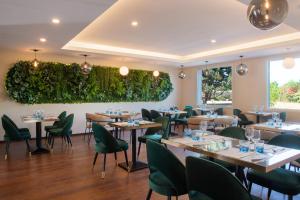 uma sala de jantar com mesas e cadeiras verdes em Golden Tulip Dieppe Hôtel & Spa em Saint-Aubin-sur-Scie