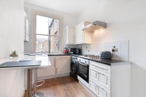 a kitchen with white cabinets and a stove top oven at 1 bed Clapham Junction apartment in London