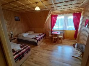 1 dormitorio con 2 camas, mesa y ventana en Żegleniówka, en Małe Ciche