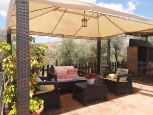 an umbrella on a patio with chairs and a couch at CASA RURAL EL CHAPARRO in Antequera