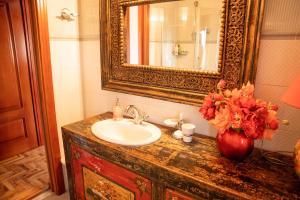 een wastafel in de badkamer met een spiegel en een vaas met bloemen bij Prestigioso Attico Panoramico Cagliari in Cagliari