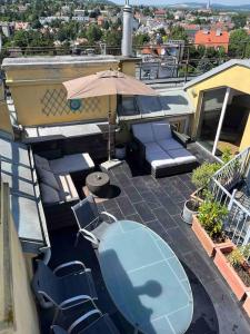 a table and chairs on a balcony with an umbrella at Rooftop - Vienna View in Klosterneuburg