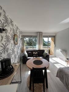 uma sala de estar com uma mesa e um sofá em Le Lagon, joli studio en bord de mer em Bénodet