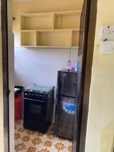 una pequeña cocina con fogones y nevera. en Happy home en Arusha