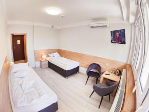 ein Hotelzimmer mit 2 Betten, einem Schreibtisch und einem Stuhl in der Unterkunft Amelia Zdroj Medical & Spa in Iwonicz-Zdrój