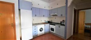 a kitchen with blue cabinets and a washing machine at Apartamento Peonia 1 in Canet de Berenguer