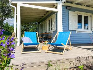 zwei blaue Stühle auf der Veranda eines Hauses in der Unterkunft Osada Aurora Całoroczne domki do wynajęcia nad jeziorem i w górach in Miszkowice