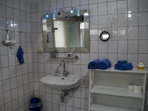uma casa de banho em azulejos brancos com um lavatório e um espelho. em B&M Apartment em Zierenberg