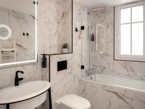 a white bathroom with a shower and a sink at Solly Hôtel Paris in Paris