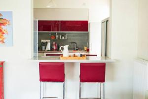 a kitchen with two red chairs at a counter at Spacious and Modern Apt in the Suburbs of Athens in Athens