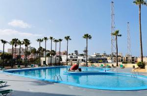 ein großer Pool mit Palmen im Hintergrund in der Unterkunft Wonderful Sea view Yomeli in Playa de las Americas