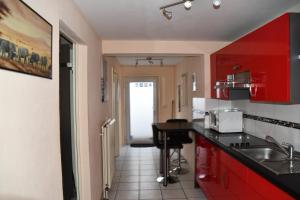 une cuisine avec des placards rouges et un comptoir noir dans l'établissement B&M Apartment, à Zierenberg