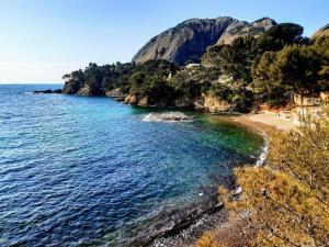 a beach next to the water with a mountain at hakuna matata in La Ciotat