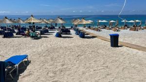 a beach with many chairs and umbrellas and the ocean at Moskato Vilas in Himare +12 photos