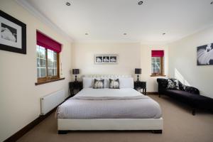 a white bedroom with a bed and a couch at Achnagairn Estate - Self-catering Mini Manors in Beauly