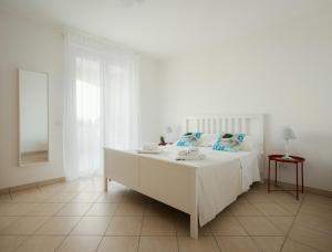 a white bedroom with a white bed with blue pillows at I Cinque Pini in Follonica