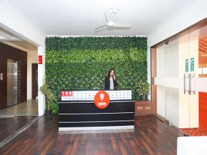 ナーシクにあるHotel O 10671 Hotel Sai Premの緑の壁前に立つ女