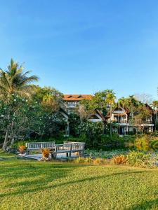 twee banken in een park met huizen op de achtergrond bij Rawi Warin Resort And Spa - SHA Extra Plus in Koh Lanta