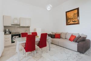 un soggiorno con divano e tavolo con sedie rosse di B&B Nuovo Reale - CENTRO STORICO a Lecce