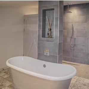 eine weiße Badewanne im Bad mit Dusche in der Unterkunft Bashall Barn in Clitheroe