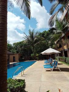 una fila de sillas y una sombrilla junto a una piscina en Naiyang Beach Hotel SHA Plus, en Nai Yang Beach