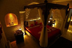 a bedroom with a canopy bed with a red comforter at Nova Cave Hotel in Ortahisar