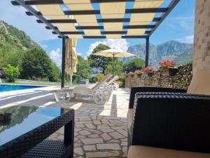 a patio with chairs and an umbrella next to a pool at Milas Trojica Kotor in Kotor